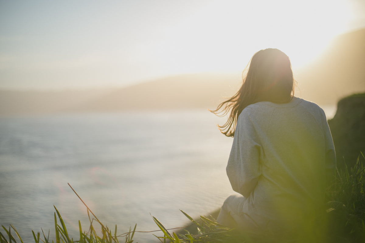 Lady sitting by water - daily grounding rituals